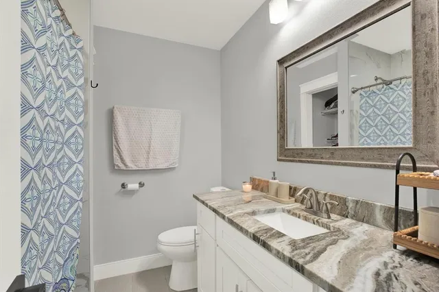 a bathroom with a granite countertop toilet sink and mirror