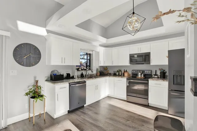 a kitchen with granite countertop stainless steel appliances a sink a stove top oven a counter space and cabinets