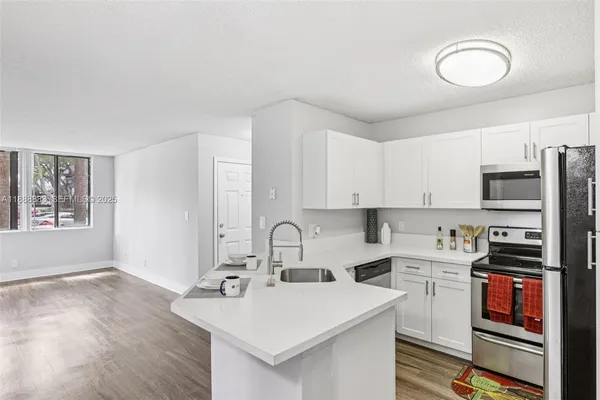 a view of kitchen and empty room with wooden floor