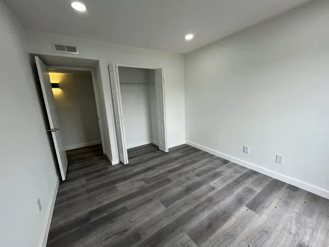 an empty room with wooden floor and entrance