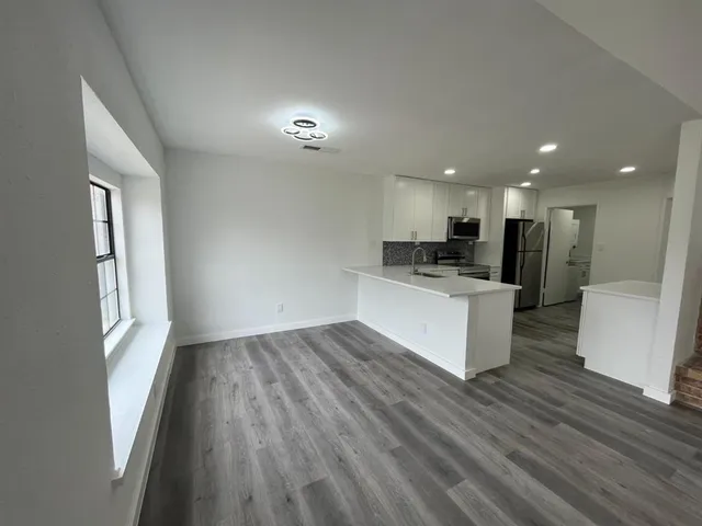 a view of kitchen with kitchen island wooden floor center island stainless steel appliances and window