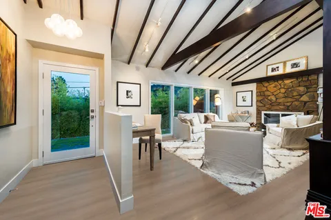 a living room with furniture a large window and wooden floor