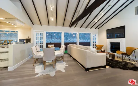 a living room with furniture a fireplace a flat screen tv and next to a window