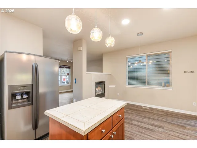 a open kitchen with kitchen island a refrigerator wooden floor and a fireplace
