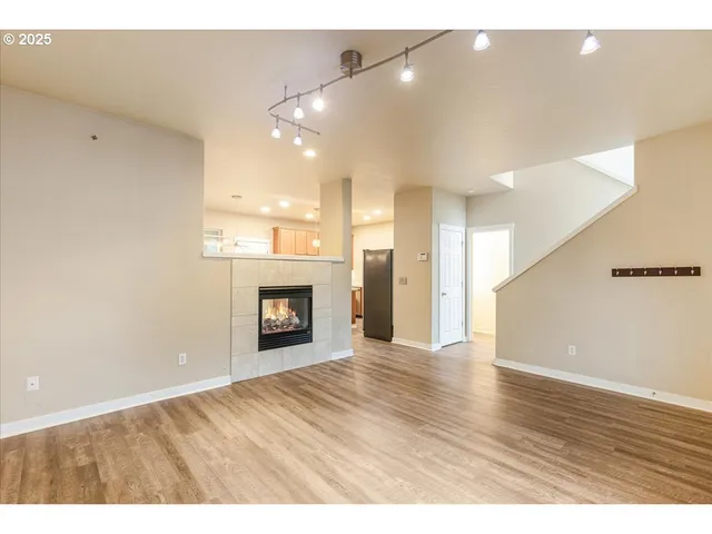 a view of an empty room and kitchen with a window
