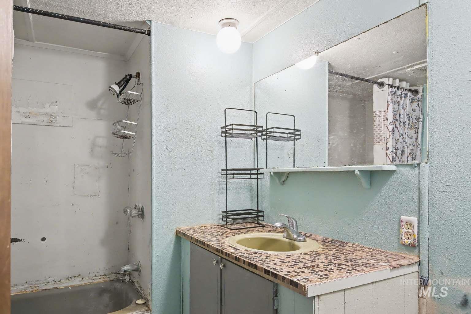 628 Burrell Avenue, Unit 5 Lewiston, ID 83501 - Photo 14 of 15 Bathroom with shower / bathtub combination with curtain, vanity, a textured ceiling, and a textured wall