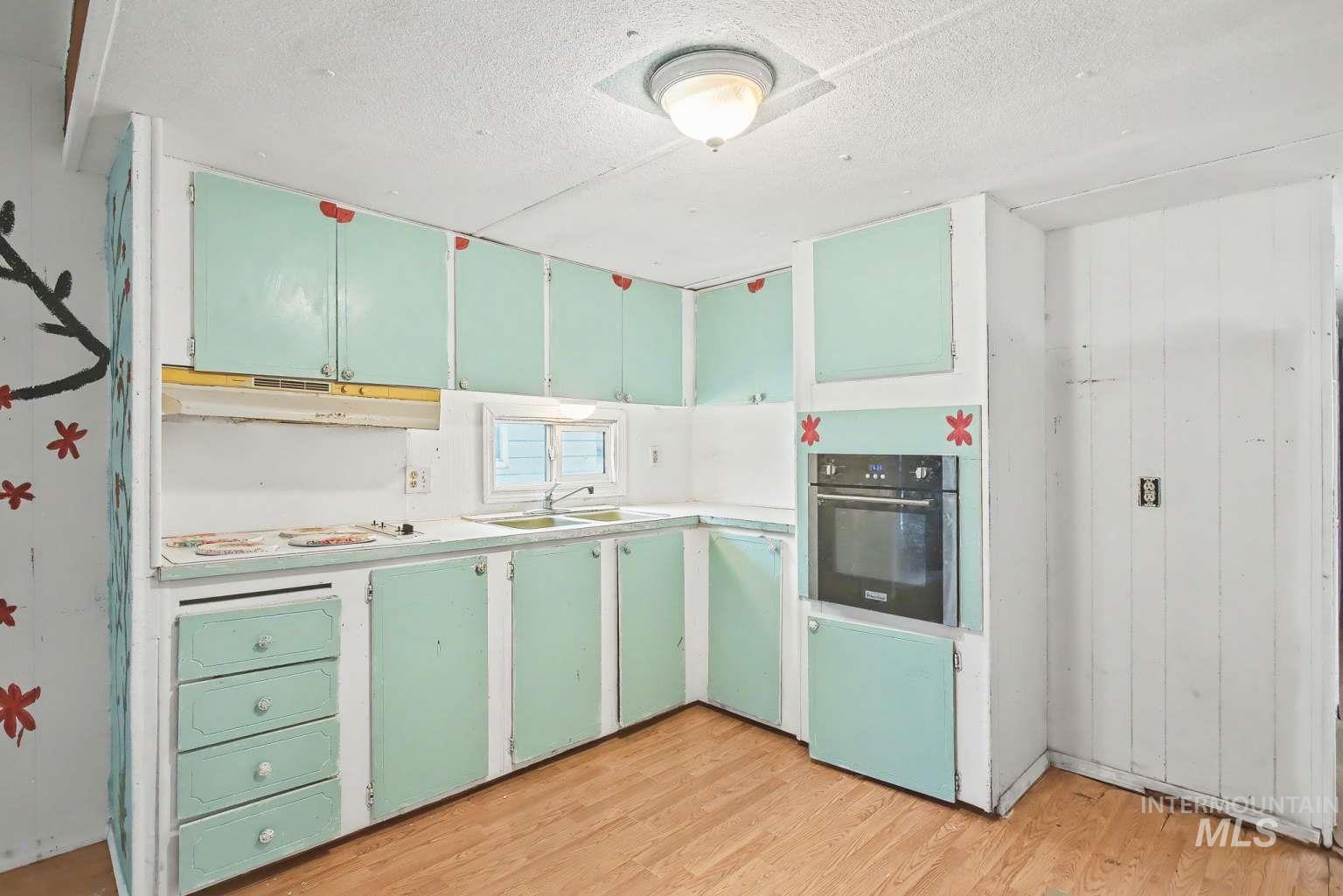 628 Burrell Avenue, Unit 5 Lewiston, ID 83501 - Photo 3 of 15 Kitchen with light countertops, oven, light wood-type flooring, a textured ceiling, and under cabinet range hood