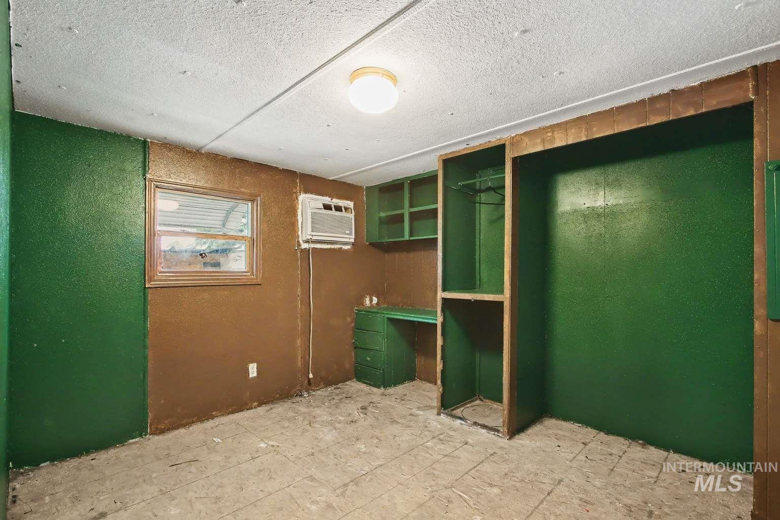 628 Burrell Avenue, Unit 5 Lewiston, ID 83501 - Photo 6 of 15 Unfurnished bedroom with a closet, a wall mounted AC, a textured ceiling, and a textured wall