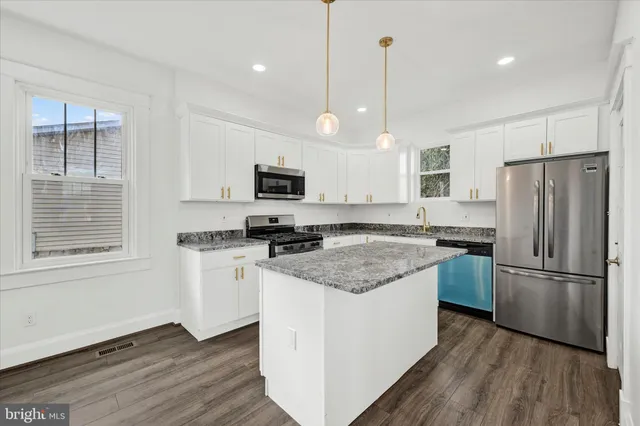 a kitchen with a refrigerator a sink and wooden floor