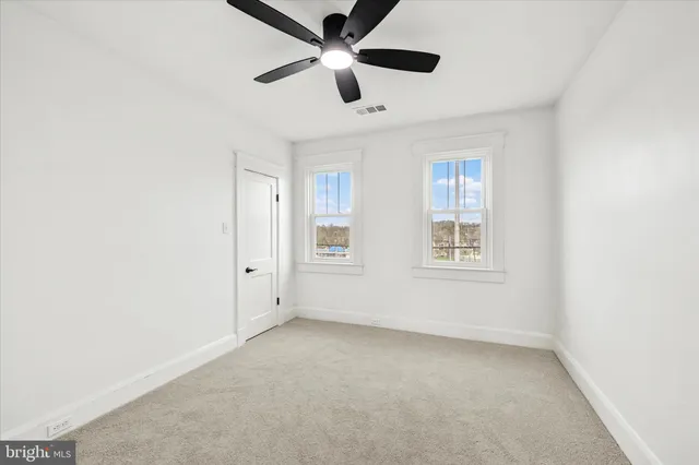 an empty room with ceiling fan and windows