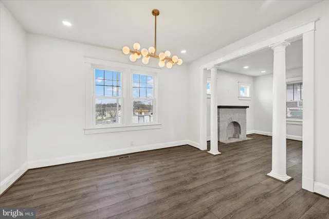 a view of a room with wooden floor fireplace and windows