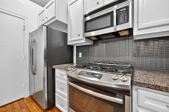 a kitchen with granite countertop white cabinets and stainless steel appliances