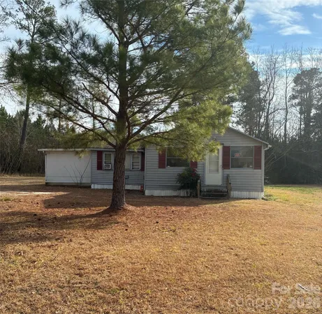 a view of a house with a yard and large tree