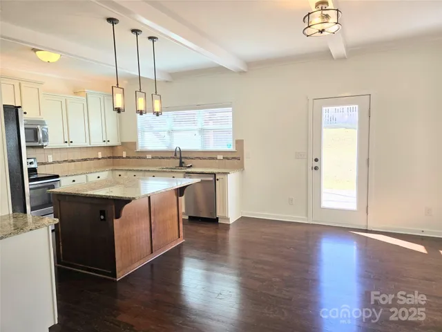 a kitchen with stainless steel appliances granite countertop a sink a stove a refrigerator and island with wooden floor