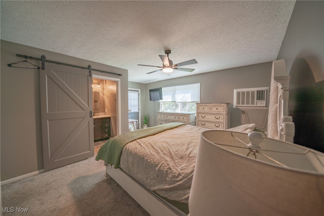 595 Moorfield Road Fairlawn, OH 44313 - Photo 16 of 50 Carpeted bedroom with a barn door, ensuite bath, a textured ceiling, and a ceiling fan