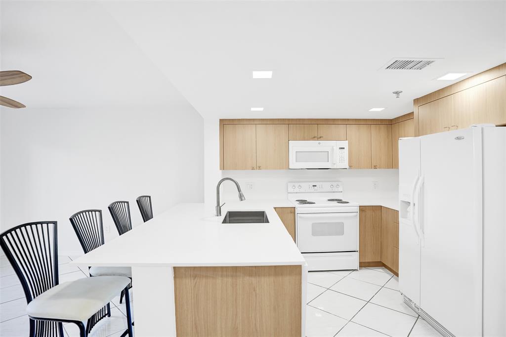 9470 Tangerine Place, Unit 404 Davie, FL 33324 - Photo 4 of 39 a kitchen with stainless steel appliances a white refrigerator a sink a stove a dining table and chairs