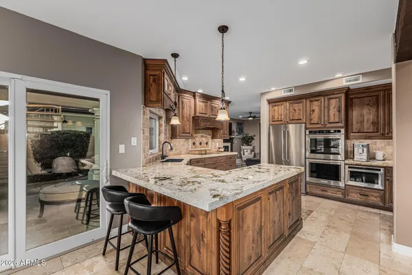 a kitchen with stainless steel appliances kitchen island granite countertop a table and chairs in it
