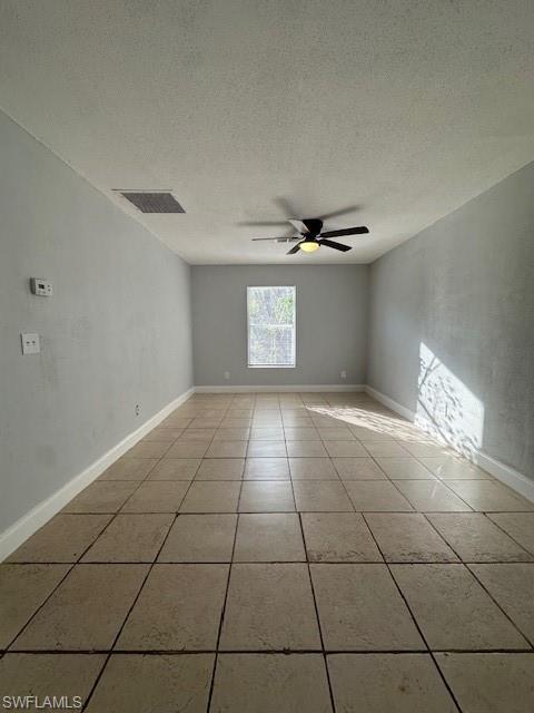2964 Francis Avenue, Unit 13 Naples, FL 34112 - Photo 3 of 5 Unfurnished room featuring a textured ceiling, a ceiling fan, and light tile patterned floors