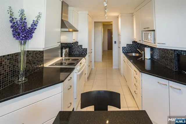 a kitchen with granite countertop a stove a sink and a refrigerator