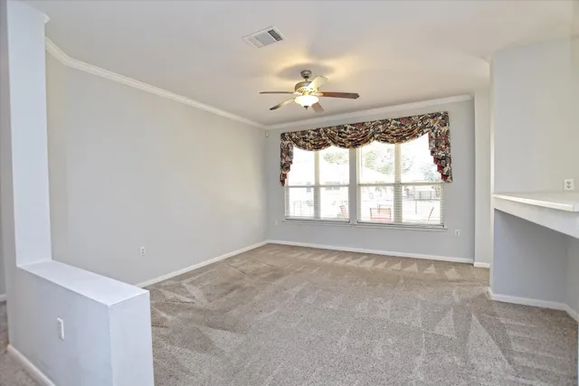 an empty room with a chandelier fan and windows