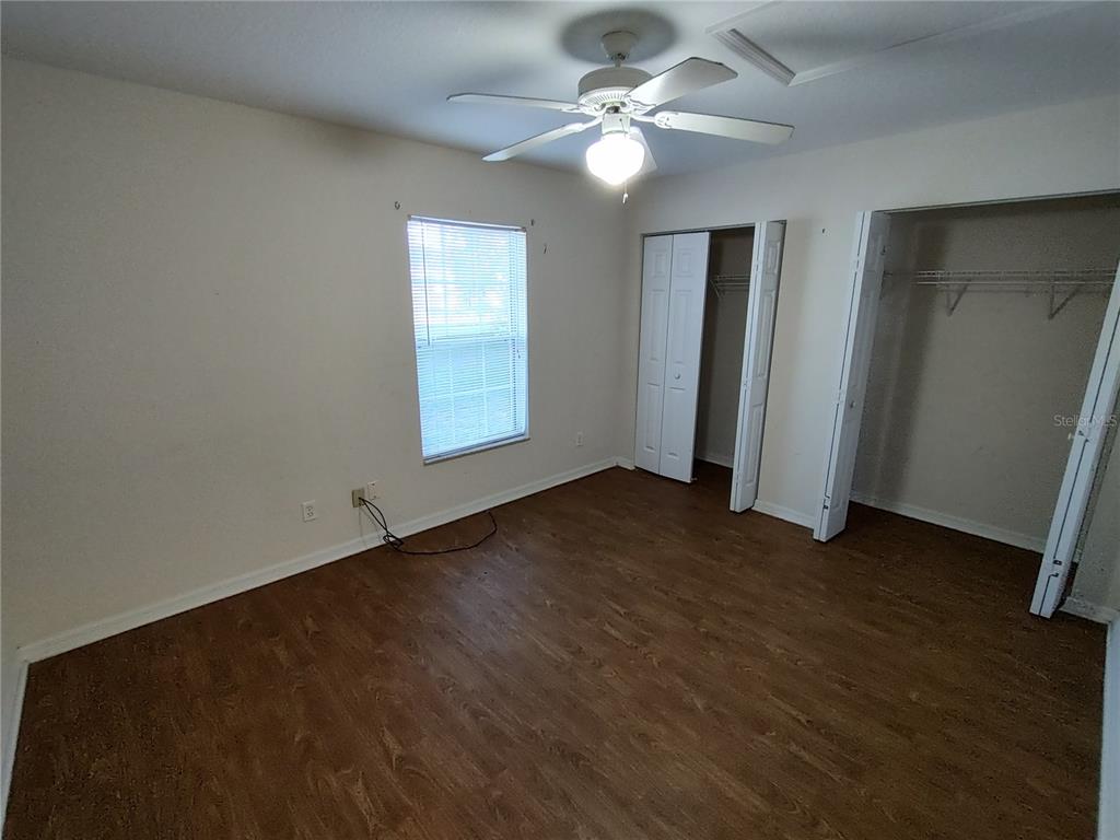 7688 Southwest 77 Place Ocala, FL 34476 - Photo 8 of 16 an empty room with wooden floor fan and windows