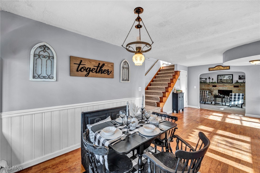 5948 South Ridge Road West Geneva, OH 44041 - Photo 8 of 16 Dining area with arched walkways, wood finished floors, a textured ceiling, stairway, and wainscoting