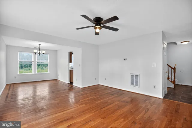 a view of empty room with wooden floor and ceiling fan