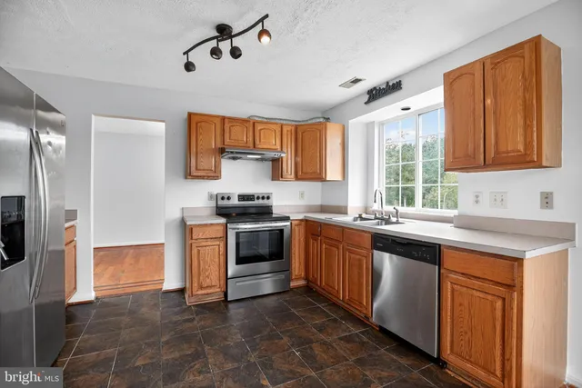 a kitchen with granite countertop a sink stainless steel appliances and cabinets