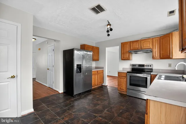 a kitchen with stainless steel appliances granite countertop a refrigerator a stove and a sink with granite countertops