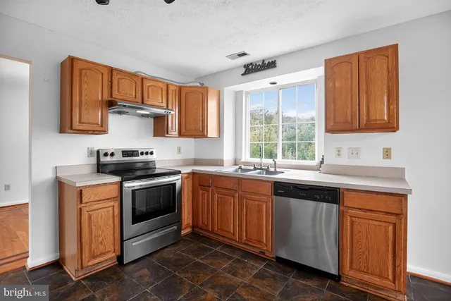 a kitchen with stainless steel appliances granite countertop a sink stove and cabinets