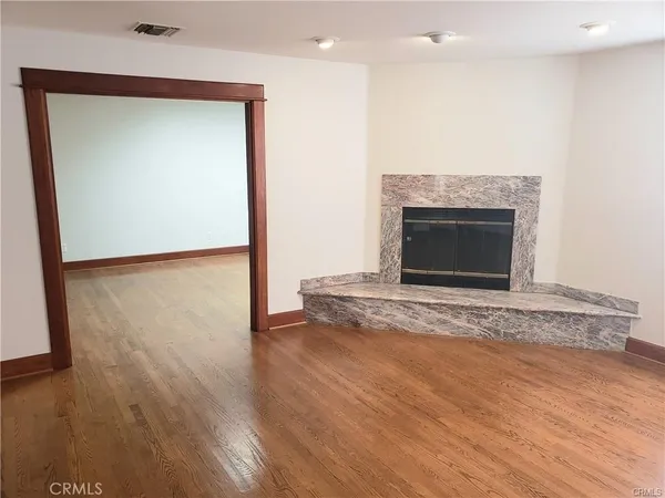 an empty room with wooden floor and a fireplace