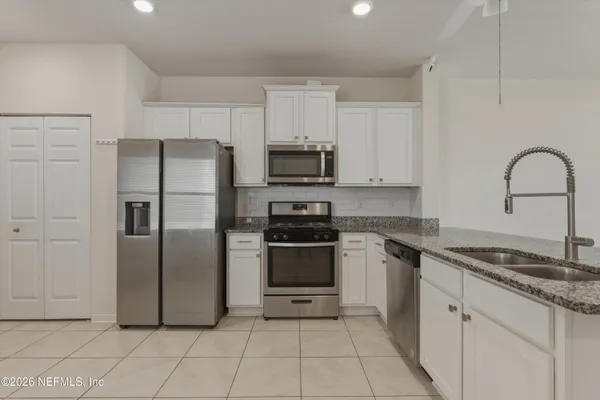 a kitchen with kitchen island granite countertop a stove top oven a sink a counter top space and cabinets