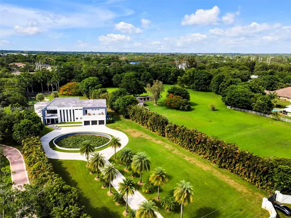 a view of a white house in a big yard with large trees