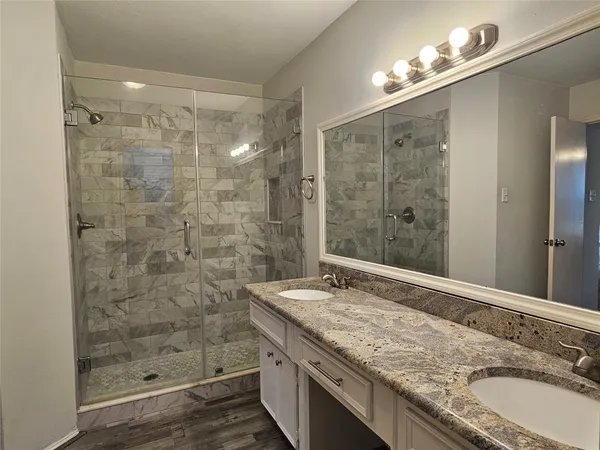 a bathroom with a granite countertop sink a mirror a shower and a bathtub