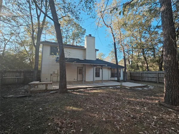 a big house with large trees and wooden fence