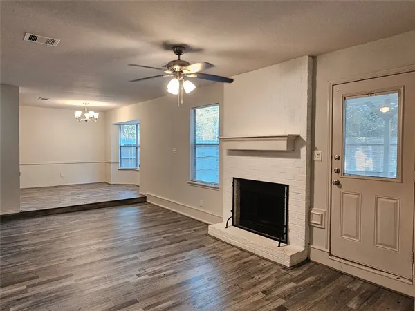 a view of an empty room with wooden floor fireplace and a window