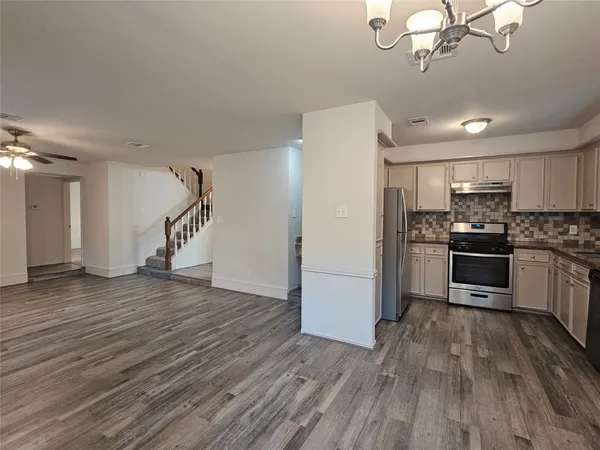 a kitchen with granite countertop a refrigerator and a stove top oven