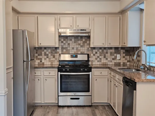 a kitchen with stainless steel appliances granite countertop a stove a refrigerator and a sink