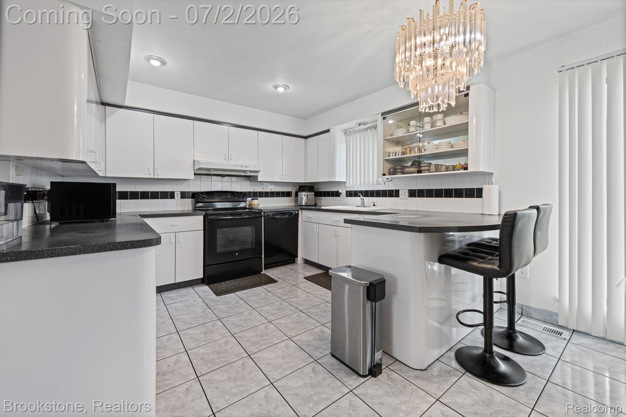 1925 Nicholas Court Warren, MI 48092 - Photo 11 of 26 Spacious kitchen featuring white cabinetry, black countertops, tile flooring, a built-in breakfast bar, and a decorative overhead light fixture