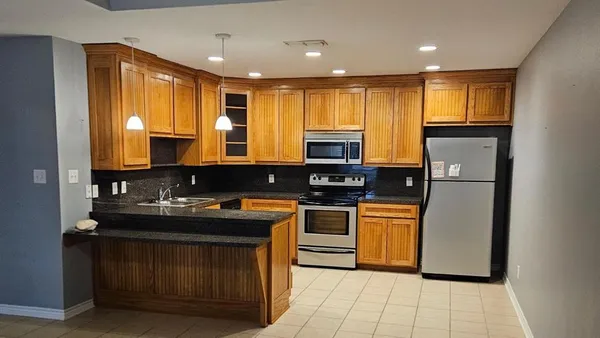 a kitchen with kitchen island granite countertop a sink appliances and cabinets