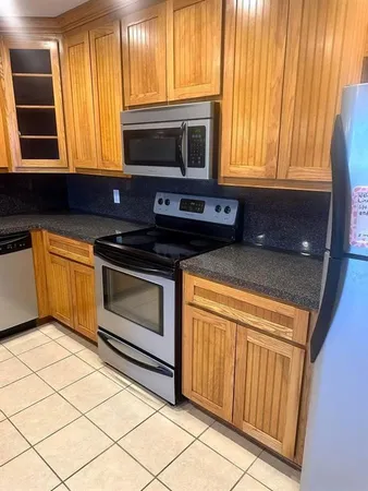 a kitchen with granite countertop a stove top oven cabinetry a sink and a microwave
