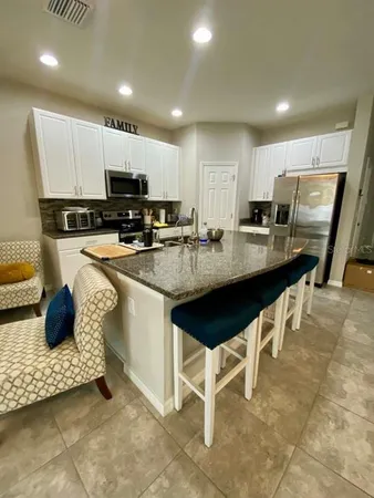 a kitchen with stainless steel appliances granite countertop a table chairs sink refrigerator and cabinets