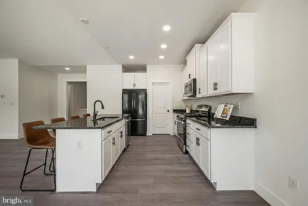 a large kitchen with stainless steel appliances granite countertop a sink and cabinets