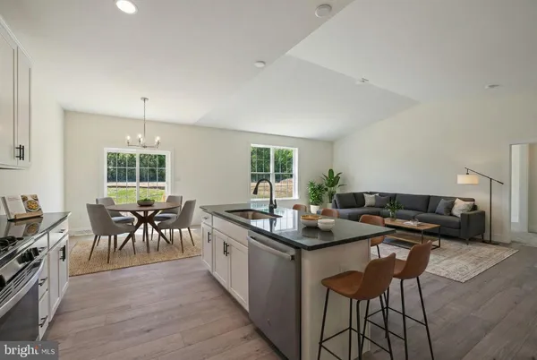 a kitchen with stainless steel appliances granite countertop table chairs stove and sink