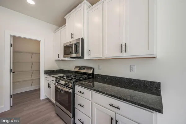 a kitchen with granite countertop white cabinets and stainless steel appliances