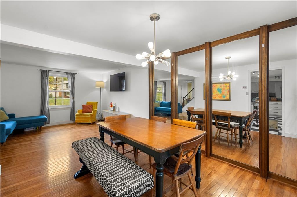 596 Clifton Road Bethel Park, PA 15102 - Photo 6 of 36 a dining room with wooden floor a chandelier a wooden table and chairs