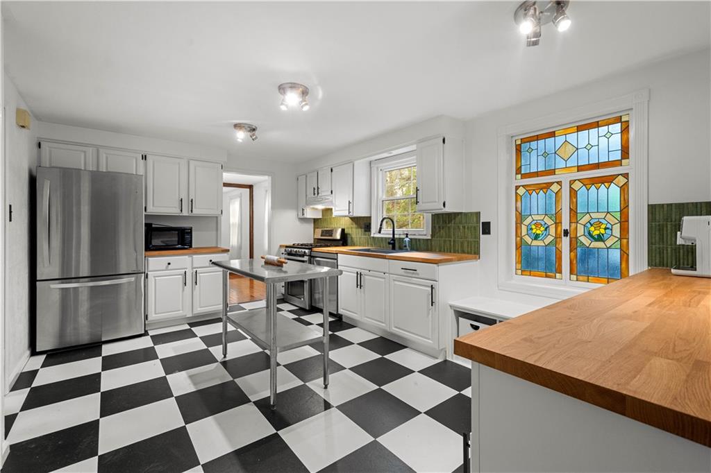 596 Clifton Road Bethel Park, PA 15102 - Photo 8 of 36 a kitchen with a checkered floor and white cabinets with stainless steel appliances