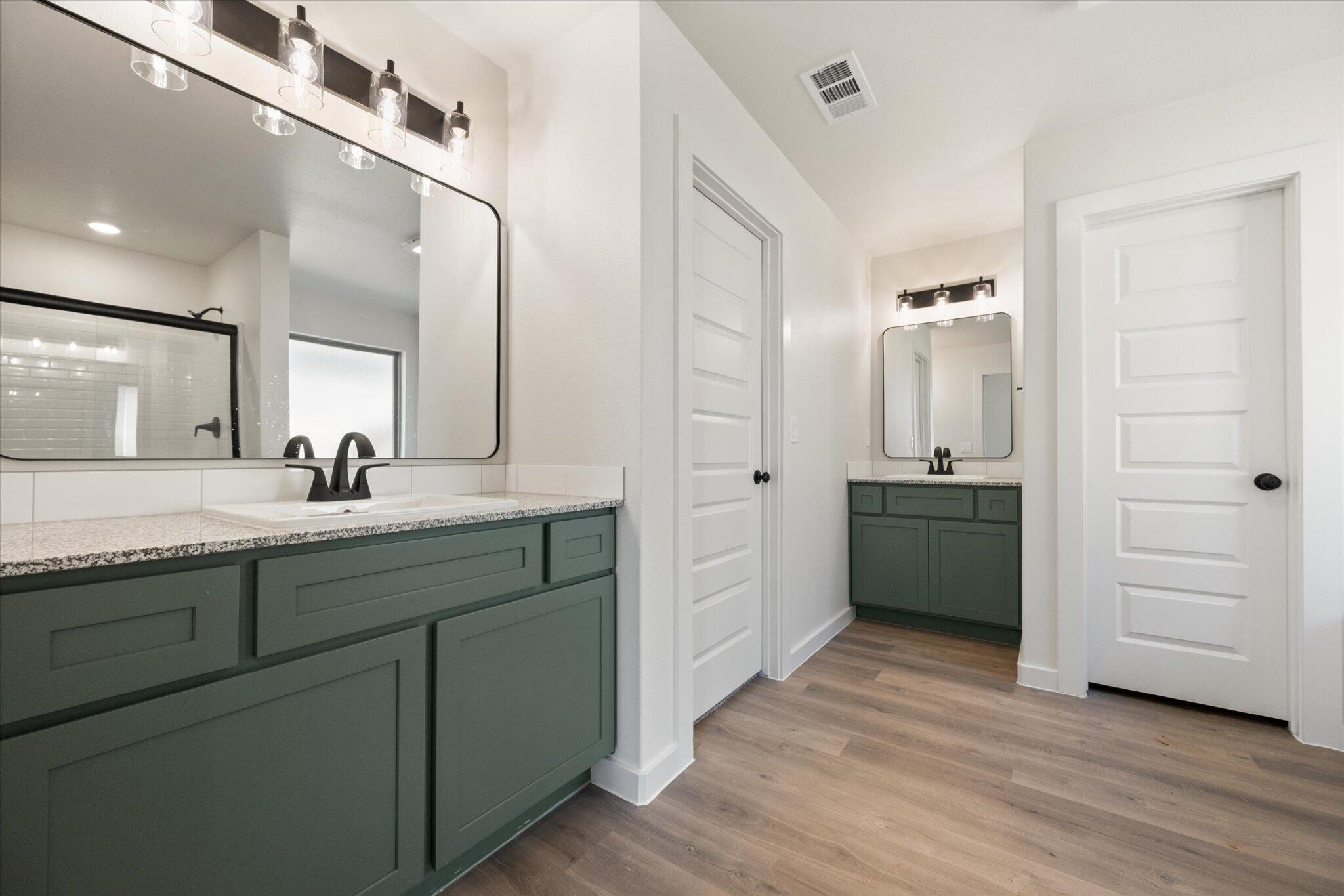 7003 53rd Street Lubbock, TX 79407 - Photo 16 of 25 a bathroom with a double vanity sink a mirror and a shower