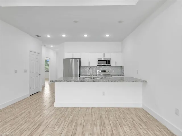 a large kitchen with stainless steel appliances a large counter top a stove and a refrigerator