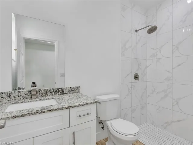 a bathroom with a granite countertop sink a toilet and a mirror